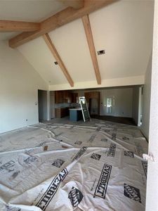 Unfurnished living room featuring beamed ceiling and high vaulted ceiling