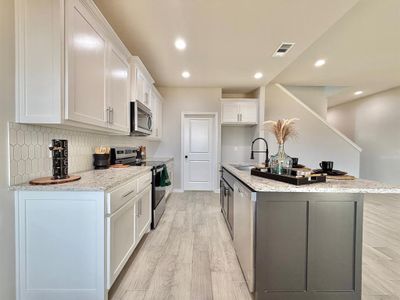 Kitchen with appliances with stainless steel finishes, sink, white cabinets, and light stone counters