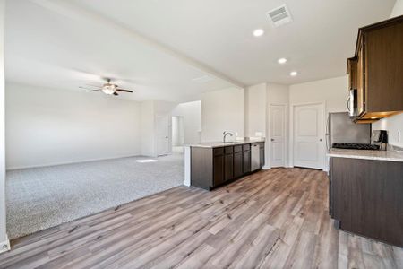 Kitchen featuring dark brown cabinets, ceiling fan, light carpet, sink, and appliances with stainless steel finishes