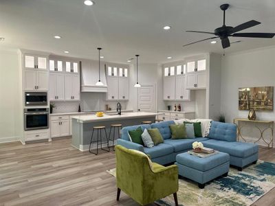 Living room featuring sink, crown molding, ceiling fan, and light hardwood / wood-style floors