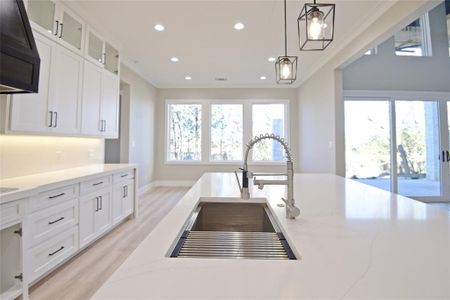 Kitchen featuring white cabinets, pendant lighting, ornamental molding, and sink