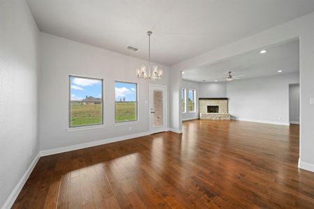 Unfurnished living room featuring ceiling fan with notable chandelier and hardwood / wood-style floors