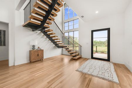 Grand entry with hardwood and floating stairwell with wood treads