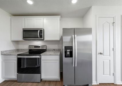 A kitchen with white cabinets and grey granite countertops.