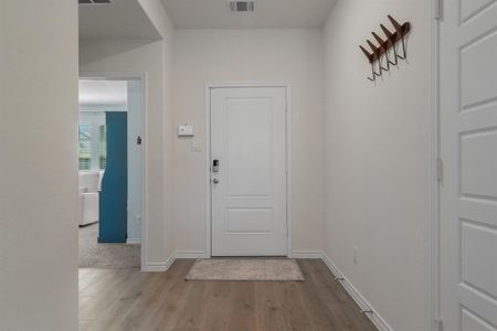 Foyer with wood finished floors, visible vents, and baseboards