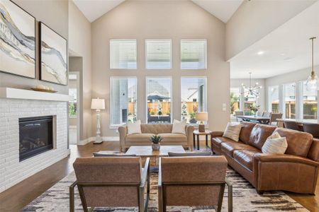 Living room featuring a chandelier, wood-type flooring, a brick fireplace, and plenty of natural light