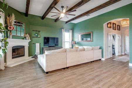 Living room with beamed ceiling, ceiling fan, and light hardwood / wood-style flooring