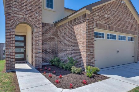 Entrance to property featuring an attached garage, concrete driveway, stucco siding, and brick siding Entrance to property featuring an attached garage, concrete driveway, stucco siding, and brick siding