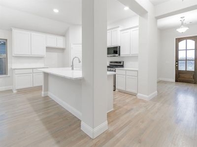 Kitchen with appliances with stainless steel finishes, light hardwood / wood-style flooring, white cabinetry, and sink