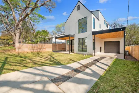 Contemporary home with stucco siding, a front lawn, driveway, fence, and an attached garage