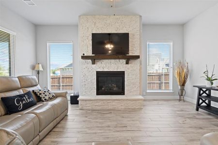 Living room with a wealth of natural light, light wood-type flooring, and a stone fireplace