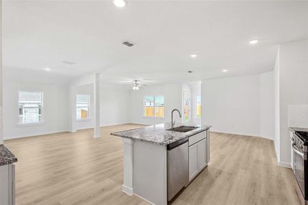 Kitchen with appliances with stainless steel finishes, light hardwood / wood-style flooring, sink, a kitchen island with sink, and ceiling fan