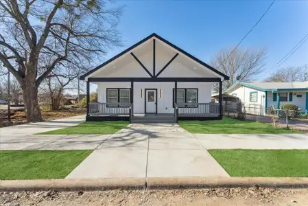 View of front facade featuring covered porch, fence, and a front lawn