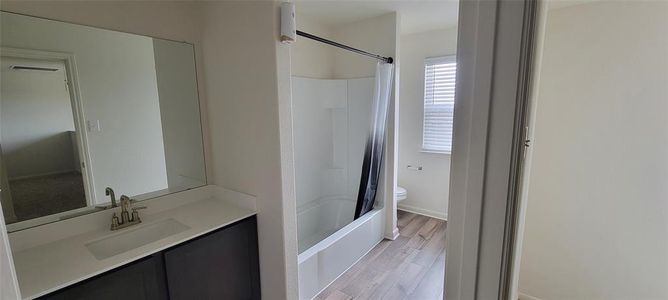 Full bathroom with shower / bath combination with curtain, toilet, wood-type flooring, and vanity