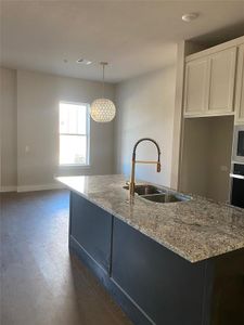 Kitchen featuring decorative light fixtures, sink, dark hardwood / wood-style floors, light stone countertops, and stainless steel oven