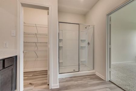 Bathroom with a shower with shower door, wood-type flooring, and vanity