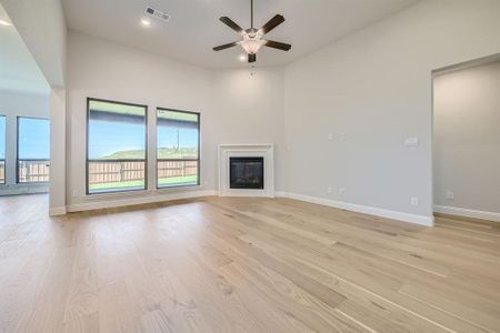 Unfurnished living room featuring ceiling fan, a towering ceiling, and light hardwood / wood-style floors