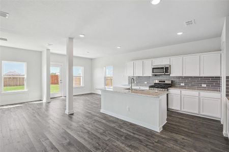 Kitchen with sink, dark hardwood / wood-style flooring, an island with sink, white cabinetry, and stainless steel appliances