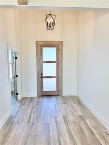 Entryway featuring baseboards, a chandelier, and wood finished floors