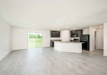 Caladesi floor plan's living room that has tile flooring, a sliding glass door and a view of the kitchen.