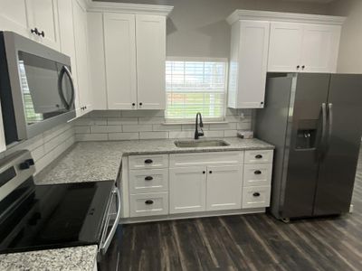 Kitchen featuring decorative backsplash, dark hardwood / wood-style flooring, sink, stainless steel appliances, and white cabinets