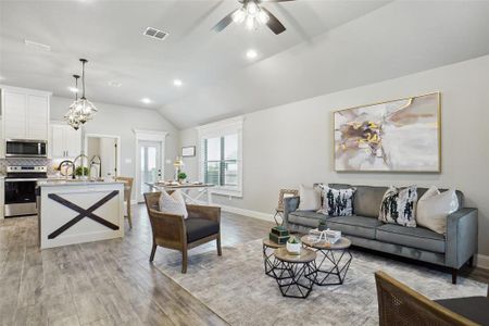 Living room featuring light hardwood / wood-style flooring, vaulted ceiling, and ceiling fan with notable chandelier