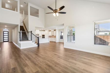 Unfurnished living room with light wood-type flooring, high vaulted ceiling, and plenty of natural light