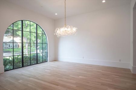 Empty room with a notable chandelier and light wood-type flooring