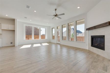 Unfurnished living room featuring ceiling fan, light hardwood / wood-style floors, and a fireplace