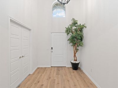 Entrance foyer featuring a towering ceiling and light hardwood / wood-style floors