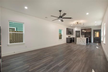 Unfurnished living room with ceiling fan with notable chandelier, dark hardwood / wood-style floors, and sink