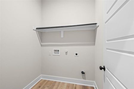 Clothes washing area with hookup for an electric dryer, hookup for a washing machine, light wood-type flooring, and gas dryer hookup