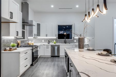 Kitchen with stainless steel appliances, wall chimney range hood, light wood-type flooring, and light stone countertops