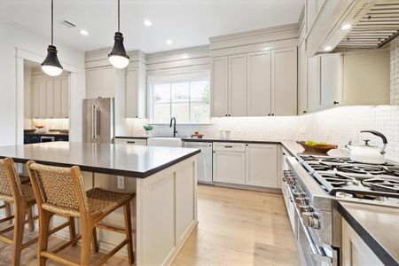 This stunning kitchen also features marble basketweave tile backsplash, a large window over the sink, mixed metal pendant lighting.