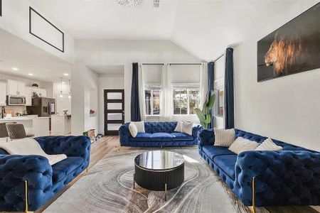 Living room with light hardwood / wood-style floors and vaulted ceiling