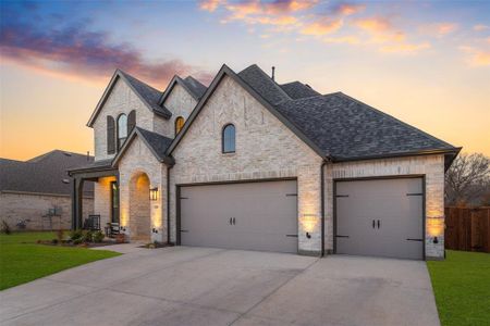 French country style house featuring a garage, driveway, a shingled roof, a yard, and brick siding