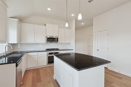 Kitchen featuring a center island, stainless steel appliances, backsplash, and light hardwood / wood-style floors