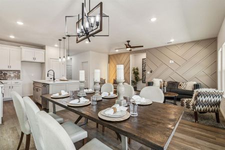 Dining space featuring sink, ceiling fan with notable chandelier, and dark wood-type flooring