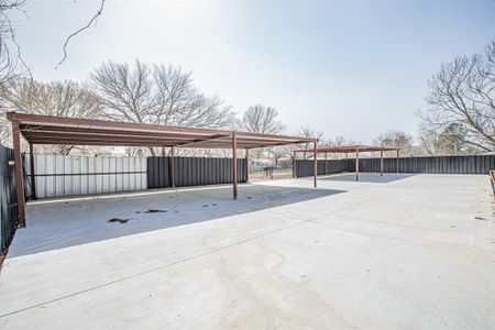 View of car parking with a carport, fence, and driveway