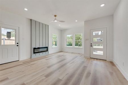 Unfurnished living room featuring ceiling fan and light hardwood / wood-style floors