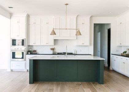 Kitchen with light hardwood / wood-style flooring, decorative backsplash, an island with sink, appliances with stainless steel finishes, and decorative light fixtures