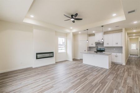 Kitchen featuring white cabinetry, a kitchen island with sink, sink, a tray ceiling, and tasteful backsplash