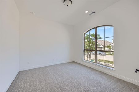 Carpeted spare room with lofted ceiling and plenty of natural light