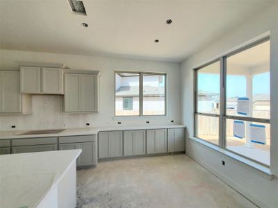 Kitchen with baseboards, light countertops, unfinished concrete flooring, and gray cabinetry