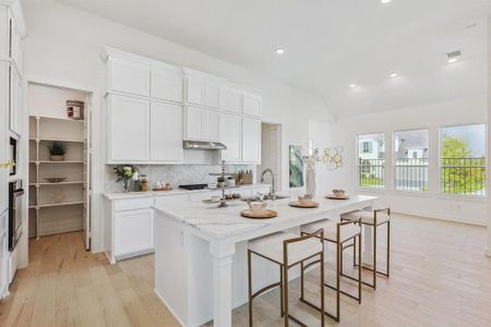 Kitchen featuring decorative backsplash, white cabinets, light stone countertops, light hardwood / wood-style flooring, and a kitchen island with sink