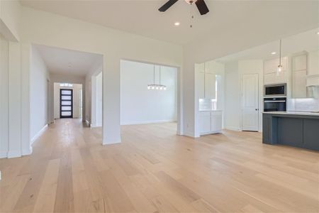 Kitchen featuring light hardwood / wood-style floors, hanging light fixtures, black oven, and stainless steel microwave