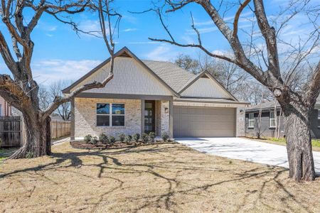 View of front of property featuring brick siding, a front lawn, fence, a garage, and driveway