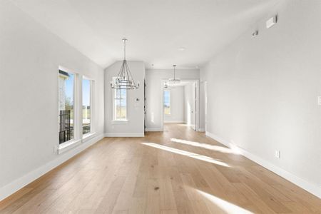 Unfurnished dining area with a chandelier, vaulted ceiling, and light wood-type flooring