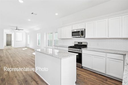 Kitchen featuring white cabinets, appliances with stainless steel finishes, dark wood-type flooring, ceiling fan, and decorative backsplash