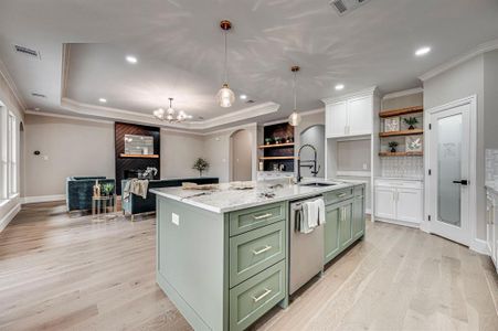 Kitchen with decorative light fixtures, light stone countertops, a raised ceiling, and dishwasher